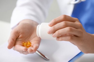 Klinikteki masada oturan vitaminli kadın doktor, yakın plan.