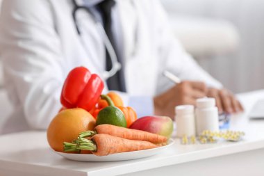 Plate with healthy vegetables on table in clinic, closeup clipart