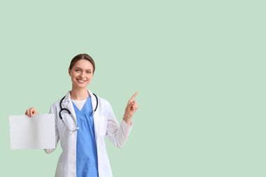 Yeşil arka plandaki bir şeyi gösteren boş kağıtlı kadın doktor.