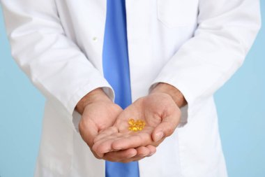 Mavi arka planda vitaminleri olan erkek doktor, yakın plan.