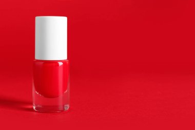 Kırmızı arka planda bir şişe oje.