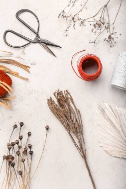 Beyaz arkaplanda yapraklı, iplikli ve makaslı kurumuş çiçekler
