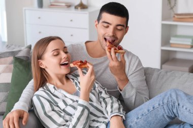 Mutlu genç çift evde lezzetli pizzalar yiyor.