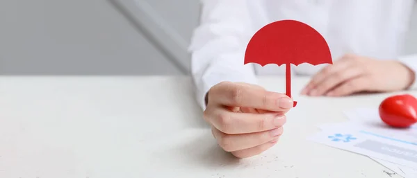 stock image Doctor with paper umbrella at white table, closeup. Insurance concept