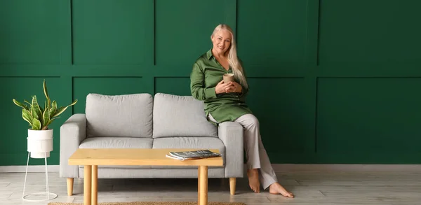 Mature Woman Drinking Tea While Sitting Sofa Green Wall Room — Stock Photo, Image