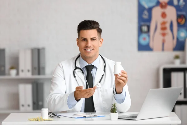 Médico Masculino Com Frasco Vitamina Sentado Mesa Clínica — Fotografia de Stock