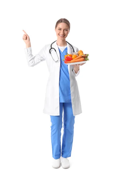 女医生 拿着一盘蔬菜指着白色背景的东西 — 图库照片