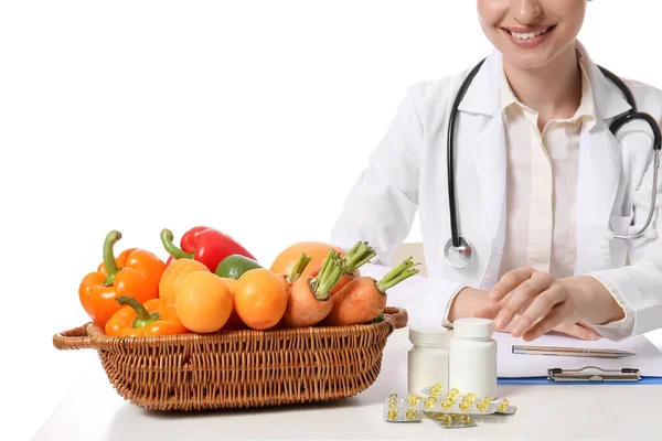 Vrouwelijke Arts Met Vitaminen Groenten Aan Tafel Witte Achtergrond — Stockfoto