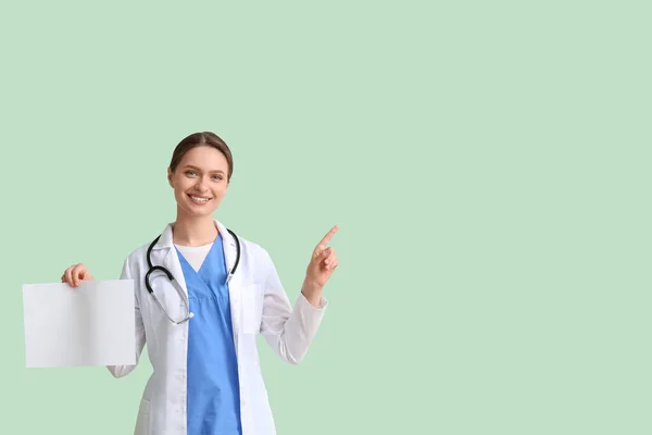Kobieta Lekarz Pustym Arkuszem Papieru Wskazując Coś Zielonym Tle — Zdjęcie stockowe