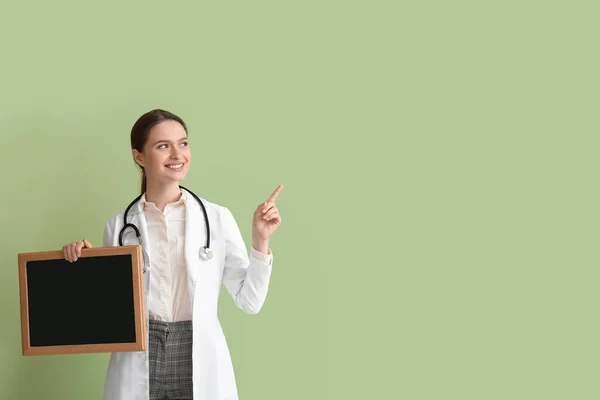 有黑板的女医生指着绿色背景的东西 — 图库照片