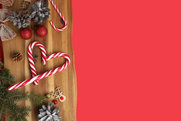 赤い背景においしいキャンディーの杖とクリスマスの装飾を持つ木製のボード — ストック写真