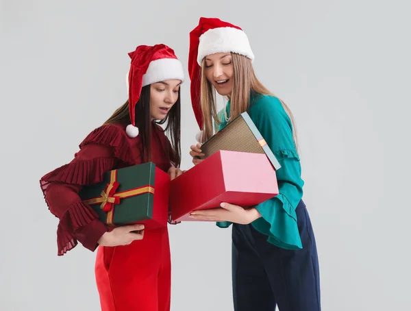 Fiatal Nők Mikulás Kalapok Karácsonyi Ajándékok Szürke Háttér — Stock Fotó