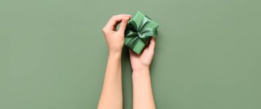 Yeşil arka planda küçük bir Noel hediyesi olan kadın elleri.