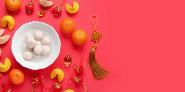 Bir kase lezzetli tangyuan, fal kurabiyeleri, mandalina ve kırmızı arkaplanlı Çin dekoru. Dongzhi Festivali