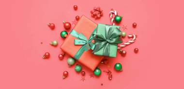 Kırmızı arka planda Noel topları olan hediye kutuları