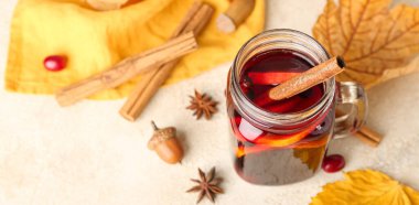 Mason kavanozu dolusu lezzetli sıcak şarap, tarçın ve arka planda sonbahar yaprakları.