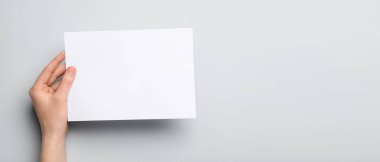 Metin için boş arkaplan üzerinde boş kağıt sayfa tutan bir kadın eli