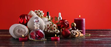 Noel kompozisyonu aroma mumları ve kozmetik ürünleri ile masada kırmızı zemin üzerinde spa tedavisi için