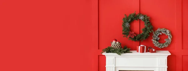 Όμορφα Χριστουγεννιάτικα Στεφάνια Κρέμονται Στον Κόκκινο Τοίχο Κοντά Στο Τζάκι — Φωτογραφία Αρχείου