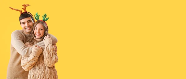 愛カップルでトナカイ角抱擁上の黄色の背景とともにスペースのためにテキスト — ストック写真