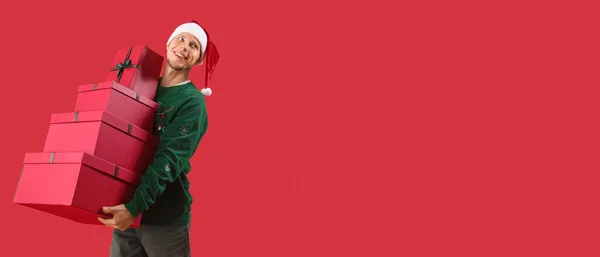 Bonito Homem Chapéu Santa Segurando Muitos Presentes Natal Fundo Vermelho — Fotografia de Stock