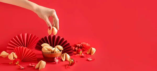 stock image Female hand with Chinese fortune cookies in bowl on red background with space for text