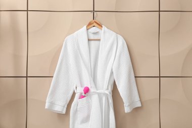 Pembe vibratörlü bornoz bej duvarda asılı.