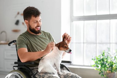 Tekerlekli sandalyede köpeği olan genç bir asker.