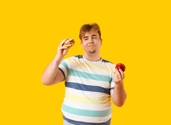 Young Overweight Man Burger Apple Yellow Background — Stock Photo, Image