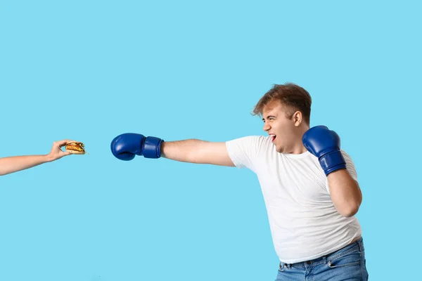 Jovem Homem Com Sobrepeso Luvas Boxe Lutando Hambúrguer Fundo Azul — Fotografia de Stock
