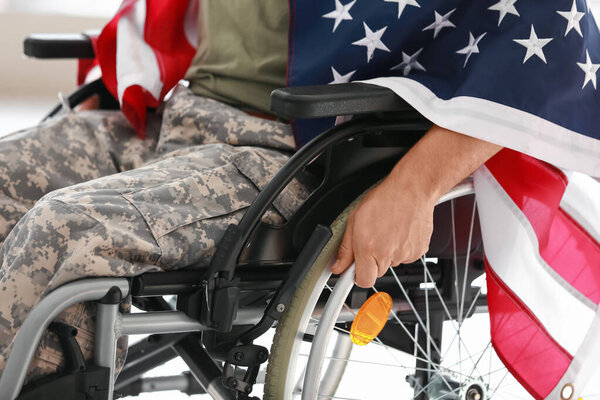 Young soldier in wheelchair with USA flag at home, closeup
