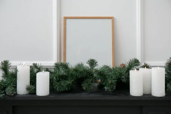 Blankrahmen Mit Weihnachtszweigen Und Kerzen Auf Kaminsims Nahe Lichtwand — Stockfoto