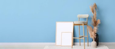 Yüksek sandalye, fotoğraf çerçeveleri ve vazolar mavi duvarın yanında kuru sazlıklar ve metin için yeri olan oda.