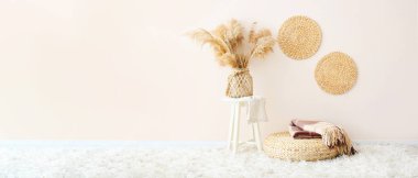 Hasır pouf, ekose ve kamışlı ışık odasının içinde, ışık duvarının yanında, metin için yeri olan vazoda.