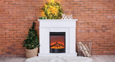 Parlak çelenkli şömine, Noel ağacı ve odasındaki tuğla duvarın yanında yakacak odun.