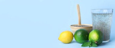 Açık mavi zemin üzerinde Chia tohumları ve narenciye meyveleri olan bir bardak su.