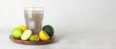 Hafif arkaplanda Chia tohumlu bir bardak su ve narenciye meyvesi.