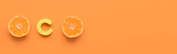 Letter C and cut citrus fruit on orange background with space for text