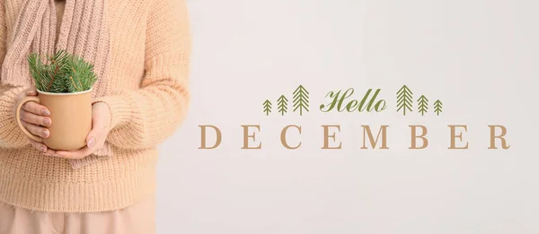 Banner with woman in warm clothes holding cup with fir tree branches and text HELLO DECEMBER
