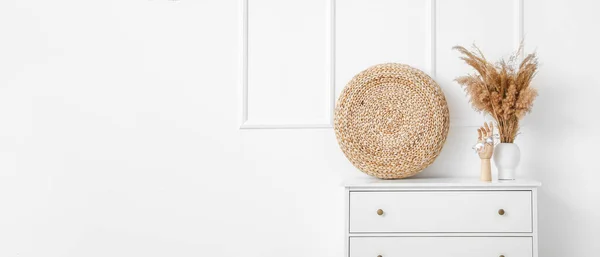 stock image Interior of room with chest of drawers and reeds in vase near white wall with space for text