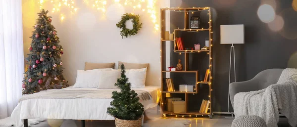 Interior of light bedroom with Christmas trees and glowing lights