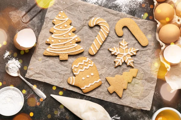 Tasty Christmas cookies and ingredients on dark background