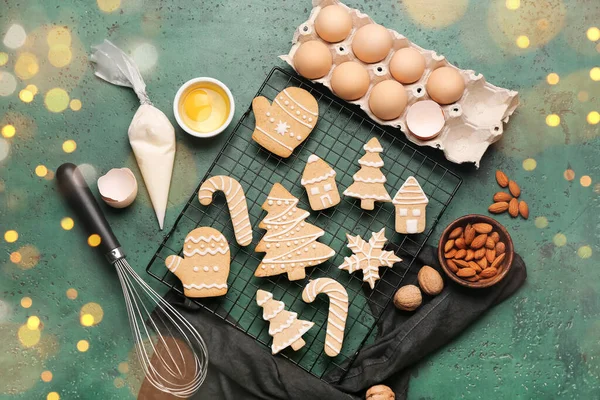 Composition with tasty Christmas cookies and ingredients on green background