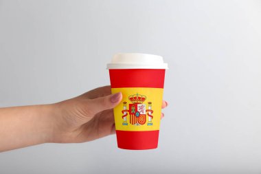 Elinde İspanyol bayrağının açık arkaplanda bıraktığı kahve fincanı olan bir kadın.