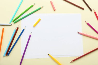 Kalemlerle dolu boş kağıt kağıtlar ve bej arka planda keçeli kalemler.