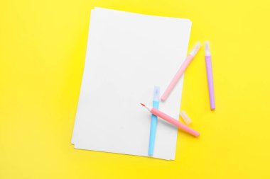 Sarı arka planda keçeli kalemleri olan boş kağıt kağıtlar.