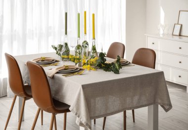 Aydınlık odada şenlikli bir masa ve çiçek dekoru.