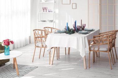 Yemek takımı ve okaliptüs dalları aydınlık odada servis edilen masada.