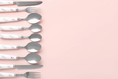 Pembe arka planda gümüş çatal bıçak takımı