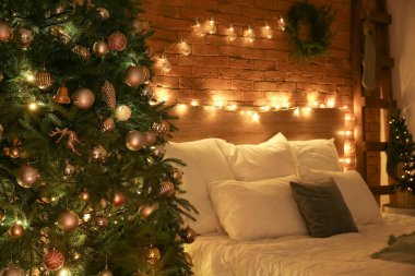 Karanlık yatak odasının içinde Noel ağaçları ve parlak ışıklar var.